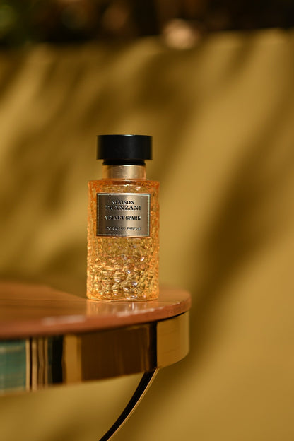MAISON FRANZANI AIR Velvet Spark – goldener Flakon auf dem runden Tisch, warm-goldener Hintergrund