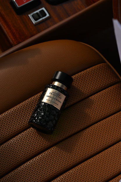 MAISON FRANZANI EARTH Absolute Roots – grüner Flakon liegt auf cognacfarbenem Leder